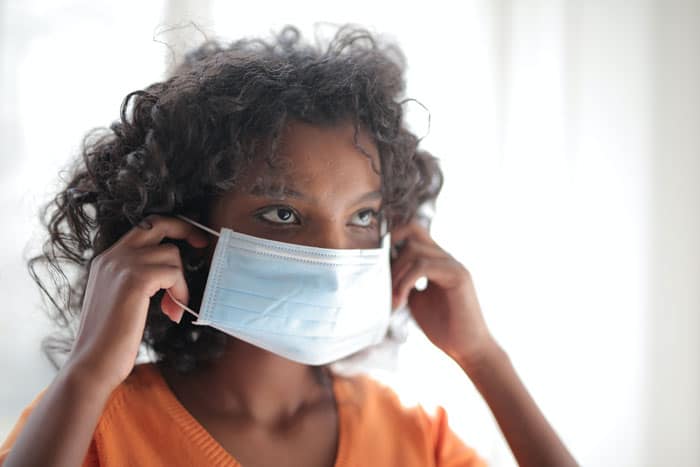 woman in orange shirt wearing a white medical mask