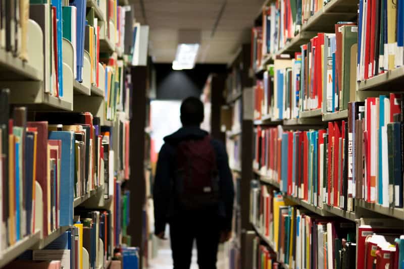 Student walking away down a row of library books