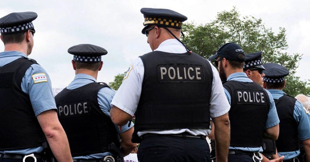 A group of Chicago police ofiicers standing together facing away from the camera
