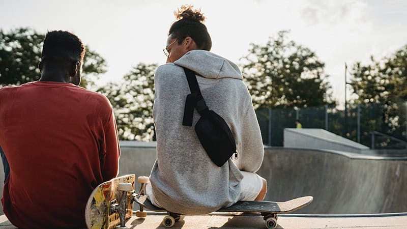Two people sit in conversation, facing away from the camera.