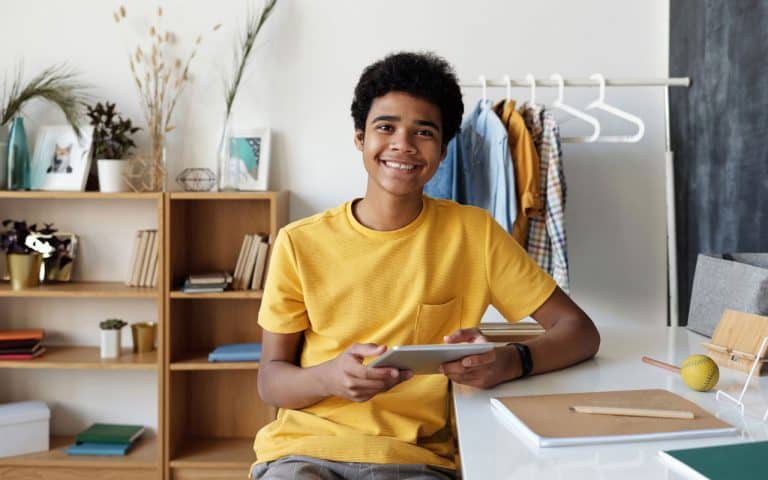 Teen boy smiling at camera, holding a tablet