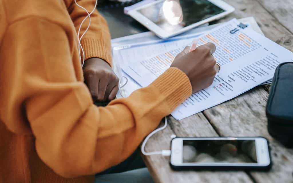 Tight view of a school student in a orange sweater studying at a table