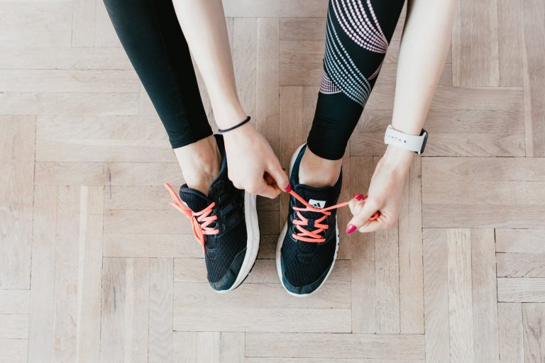 crop young sportswoman tying sneakers on floor