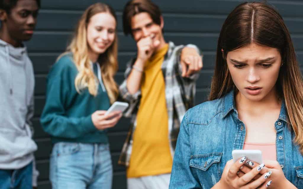 A teen girl being harassed and laughed at by 3 other teens