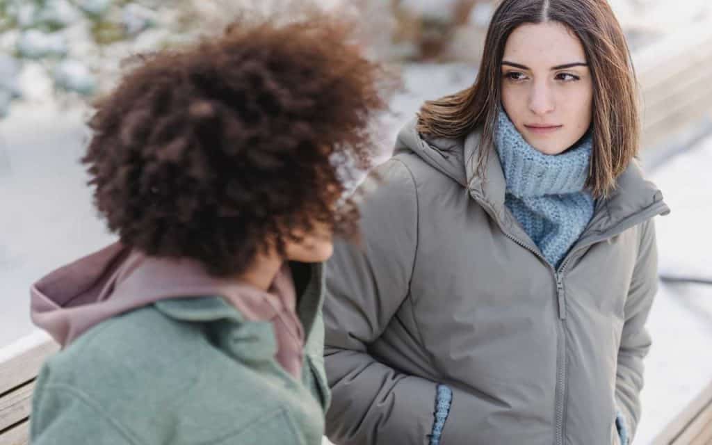Two young women on a park bench having a serious conversation
