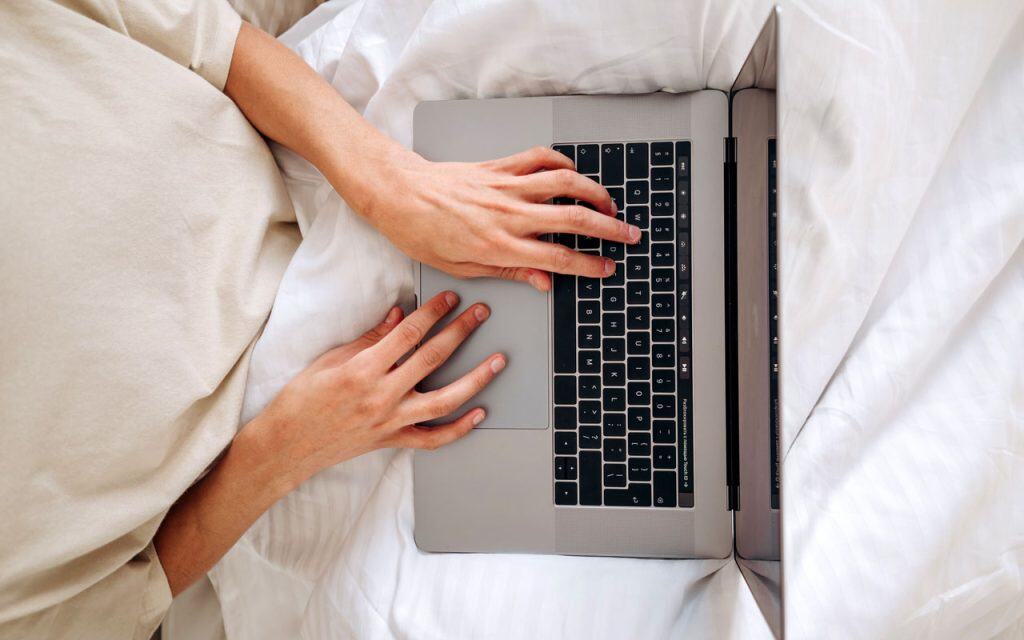 A pair of white-passing hands on a laptop keyboard