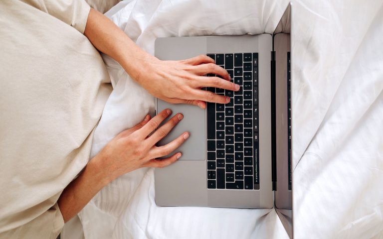 A pair of white-passing hands on a laptop keyboard
