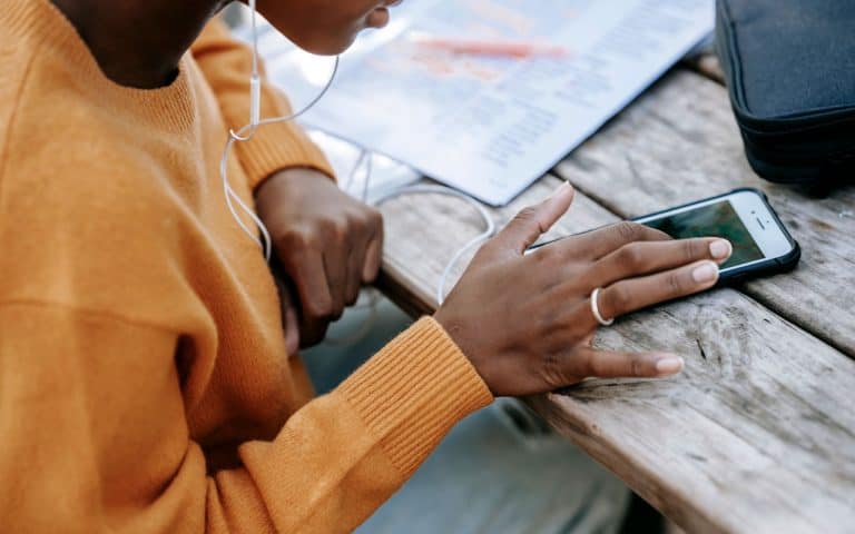 A person of color scrolls on their phone