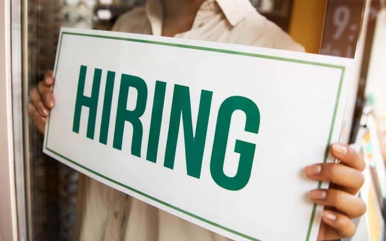 person with hiring sign by window
