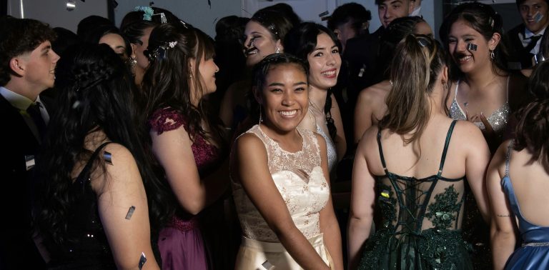 Teens at prom in a group smiling.