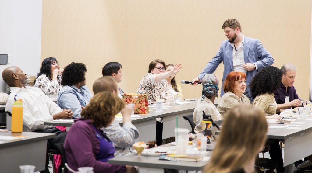 A participant at A CAASE of Empowerment raises her hand, asking a question into a microphone.