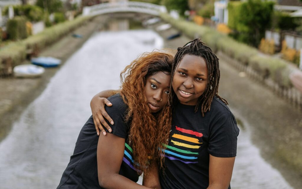A couple poses together for a photo, both wearing matching shirts with rainbows on them.