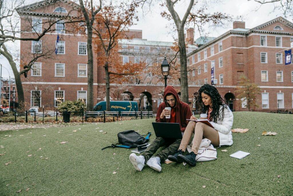 Two college students sit outside together on campus studying.