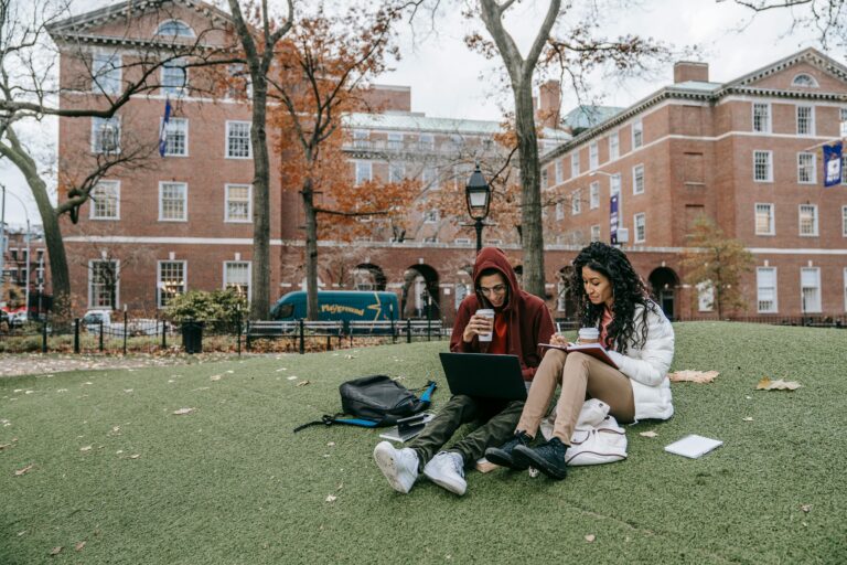 Two college students sit outside together on campus studying.