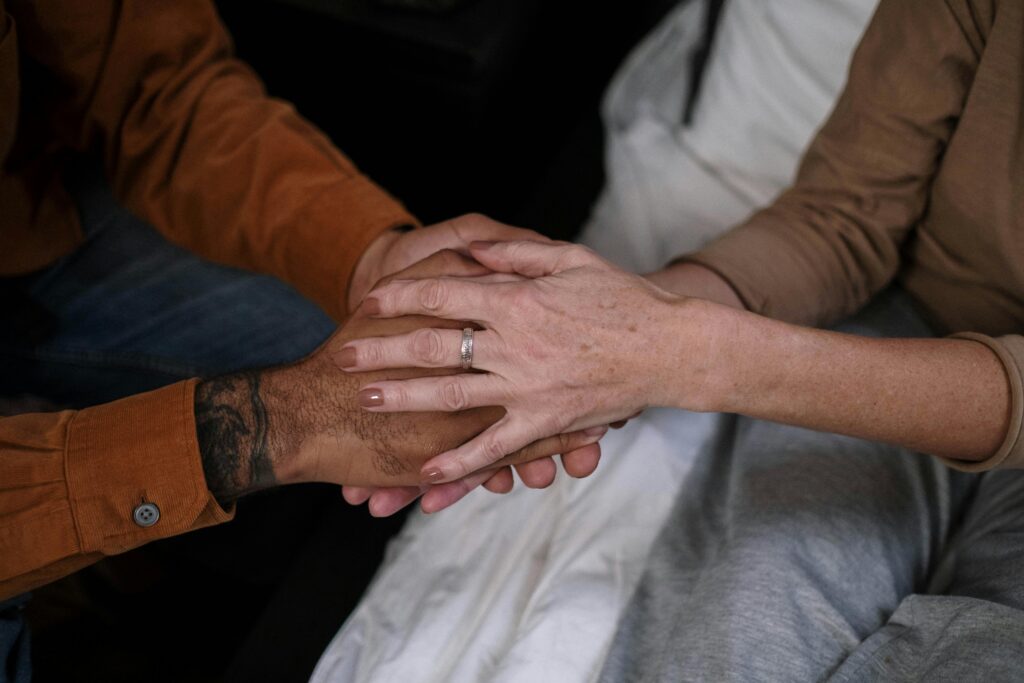 A photo shows two sets us hands sitting towards each other, clasped.