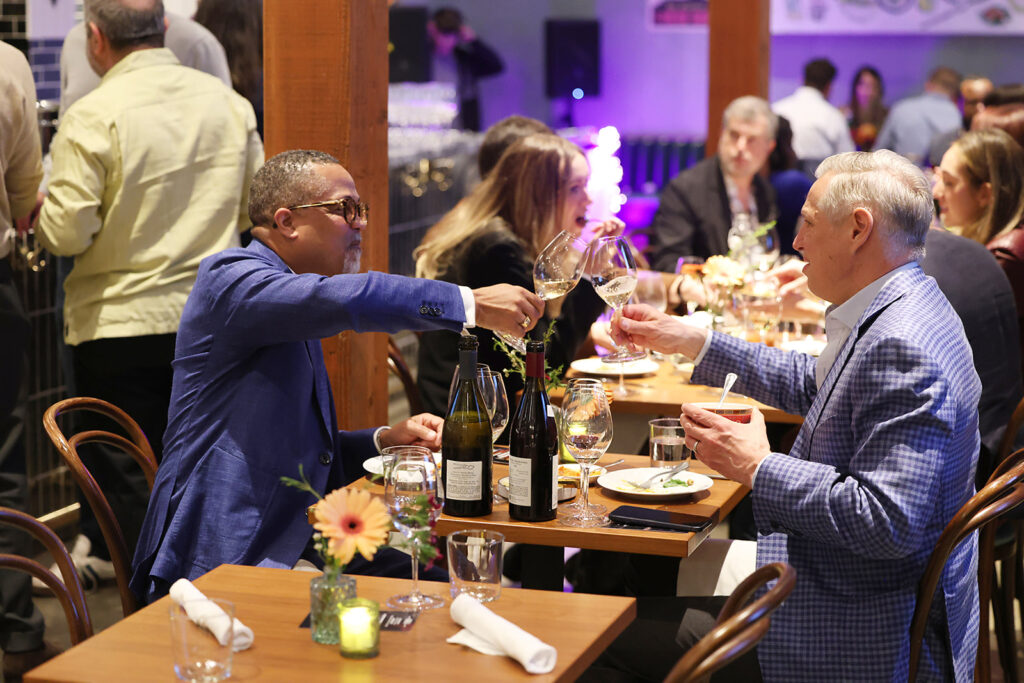Two guests at Provenance sit together and cheers their wine glasses.